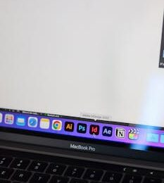 A detailed view of a MacBook Pro displaying Adobe InDesign and other design tools on screen.