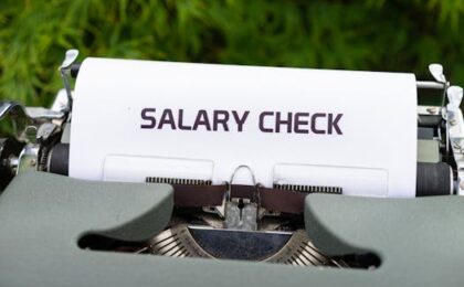 Close-up of a vintage typewriter typing 'Salary Check' on paper, symbolizing payroll and finance.